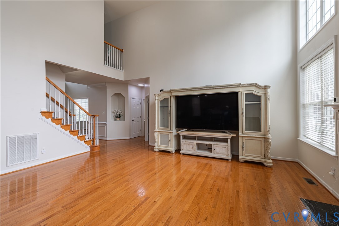 Open-concept living space featuring high ceilings and wood-finish flooring Open-concept living space featuring high ceilings and wood-finish flooring