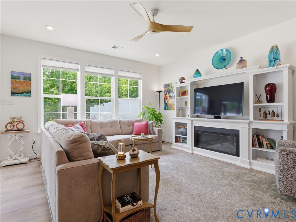 Beautiful great room with expansive windows providing abundant natural light, updated ceiling fan, and stylish wall cabinet with electric fireplace. Beautiful great room with expansive windows providing abundant natural light, updated ceiling fan, and stylish wall cabinet with electric fireplace.
