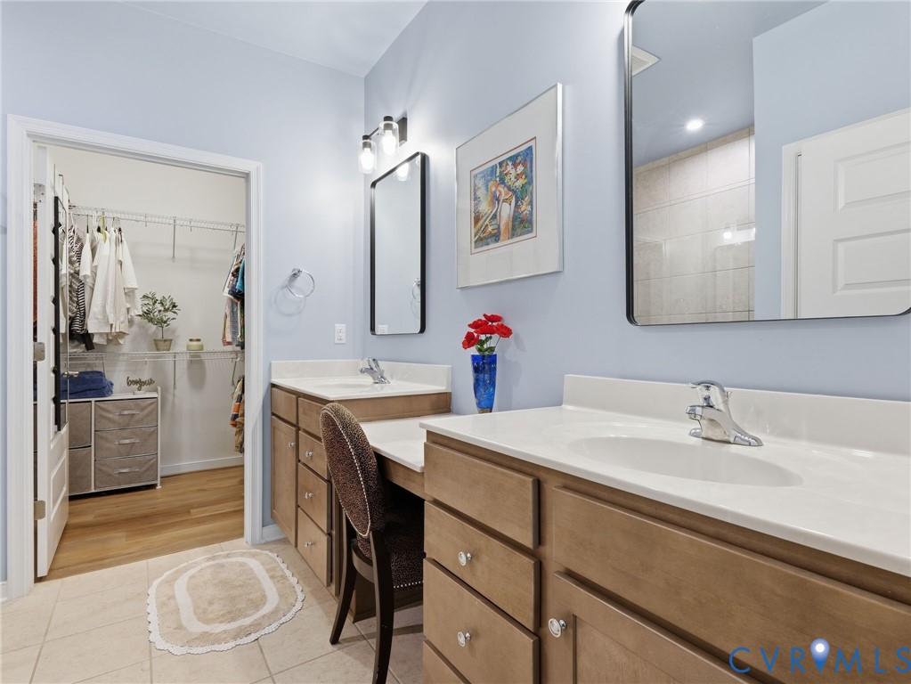 A refined primary bath featuring dual vanities, a sleek glass shower, and a sizable water closet for added privacy.