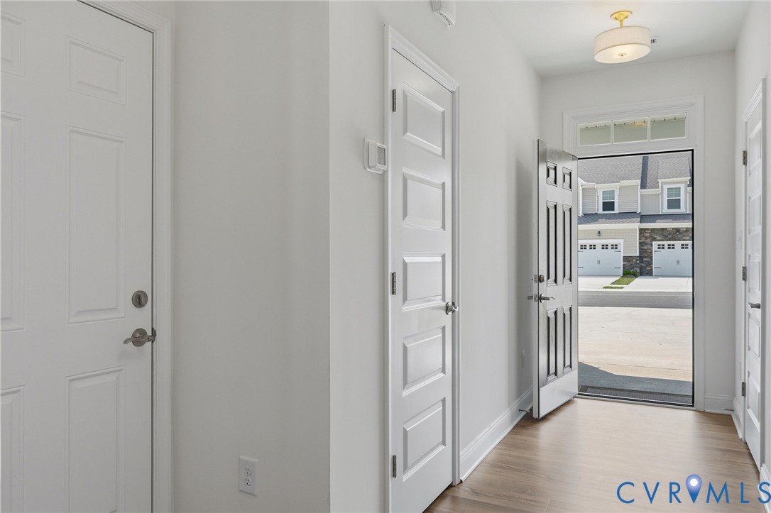 Entryway featuring wood-finish flooring, white paneled doors, and a decorative semi-flush mount ceiling fixture