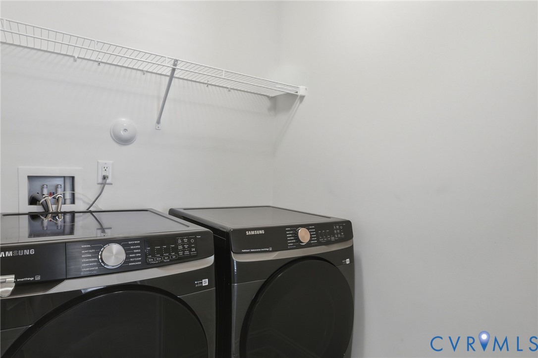 Dedicated laundry area with a wire shelving unit, electrical outlet, and water hookups