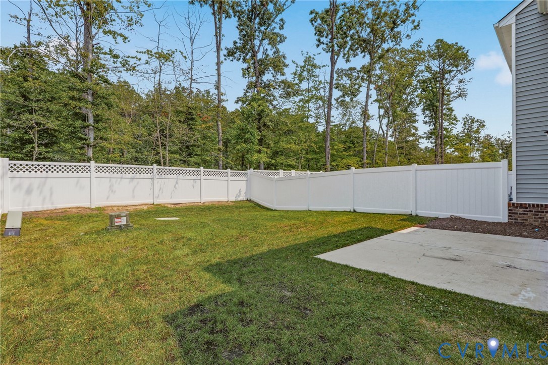 Expansive backyard with a white privacy fence, featuring a lattice top section