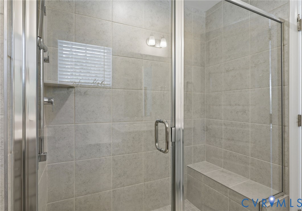 Glass-enclosed shower featuring large format tile, a built-in bench, and a recessed soap niche