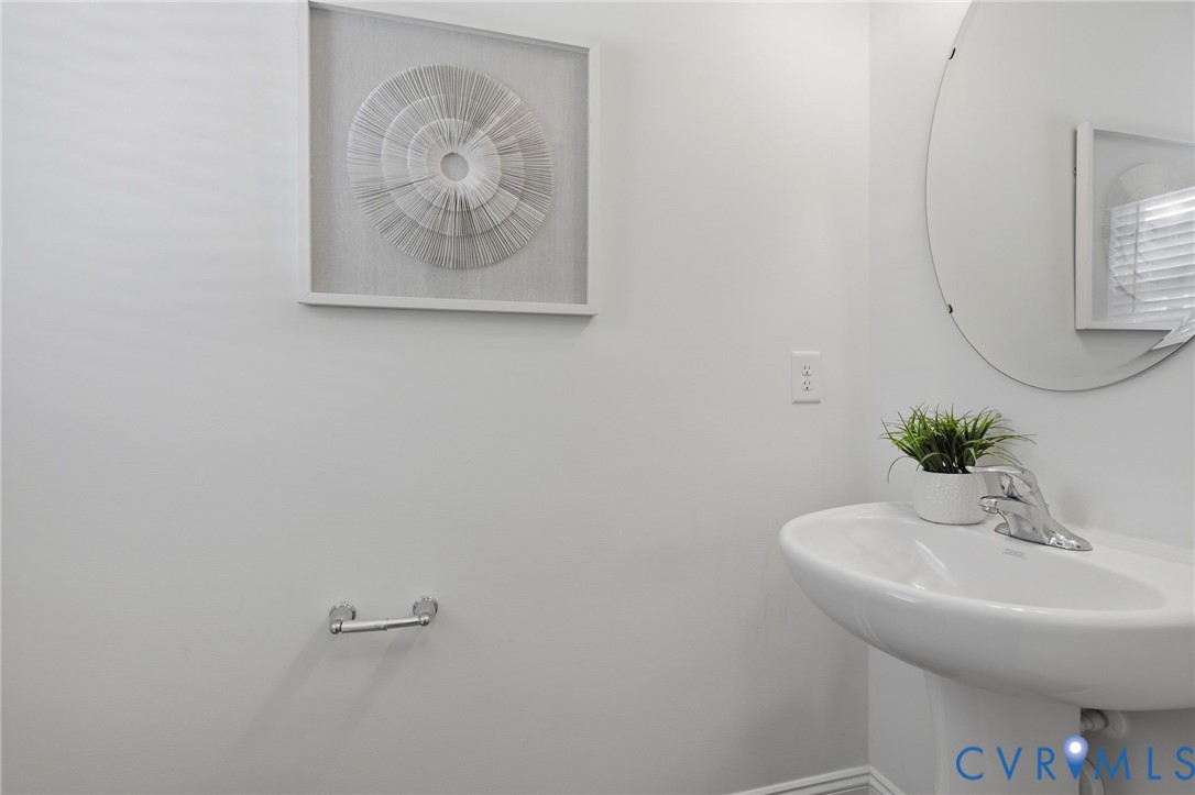 Pedestal sink with chrome faucet and circular mirror