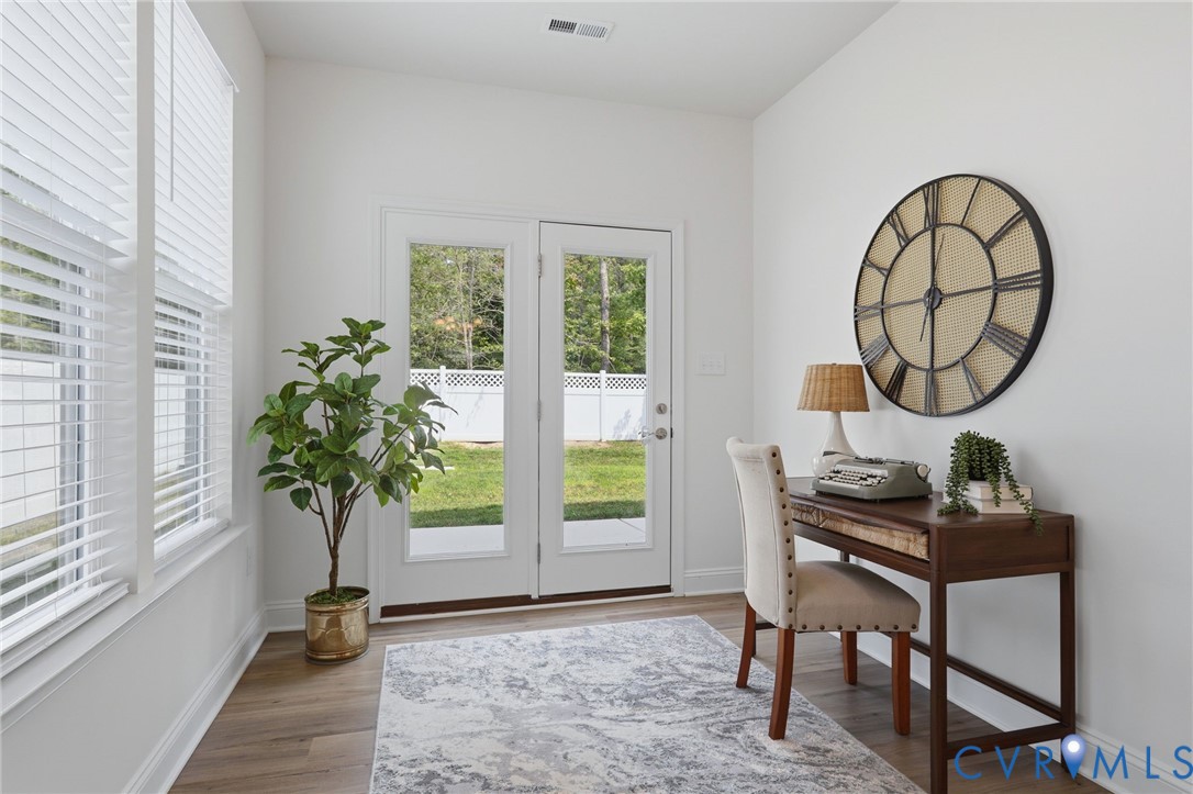 Room featuring wood-finish flooring, white walls, and bright natural light from multiple windows