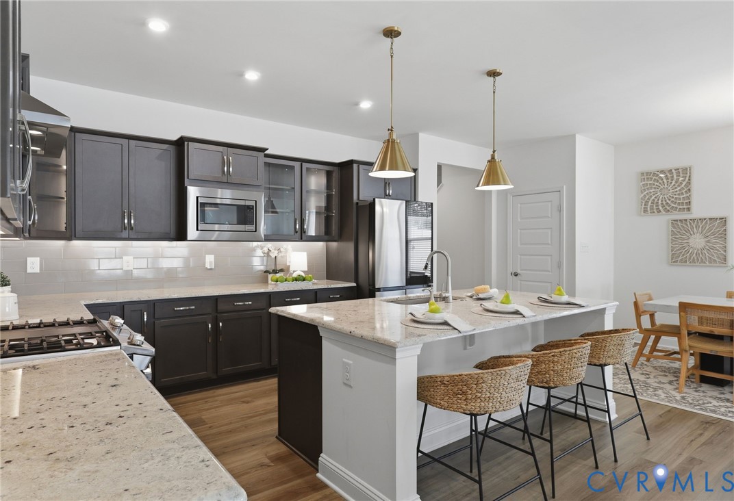 Modern kitchen featuring dark cabinetry, stainless steel appliances, and light stone-finish countertops