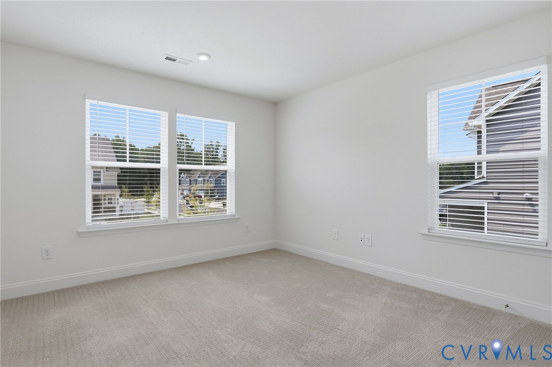 Carpeted room featuring multiple windows with blinds, white trim, and light-colored walls