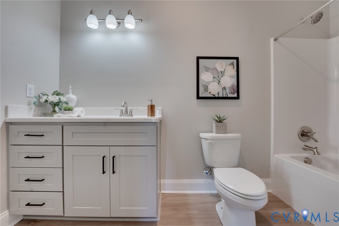 Bathroom featuring a light gray vanity with black hardware, white countertop, and a built-in tub with a shower
