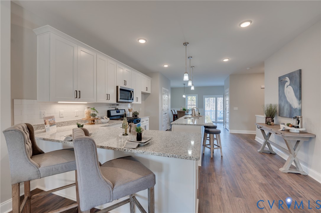 Spacious kitchen featuring white shaker cabinetry, speckled countertops, and a subway tile backsplash