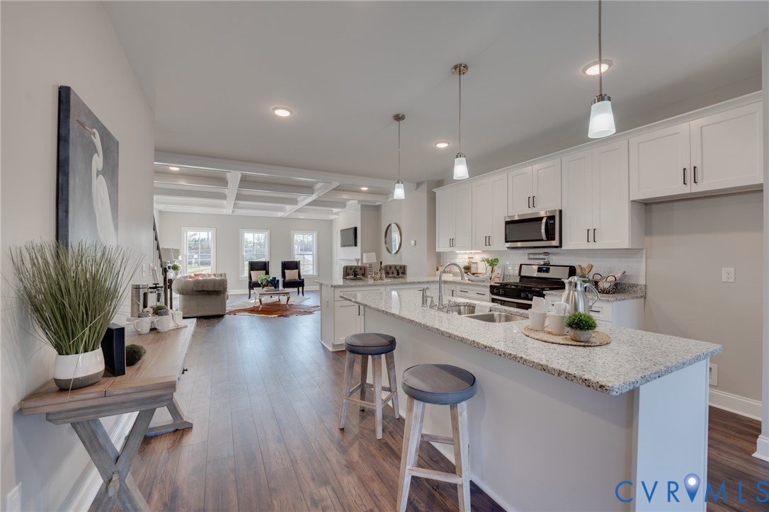 Bright kitchen featuring white cabinetry, stainless steel appliances, and a spacious island with granite countertops