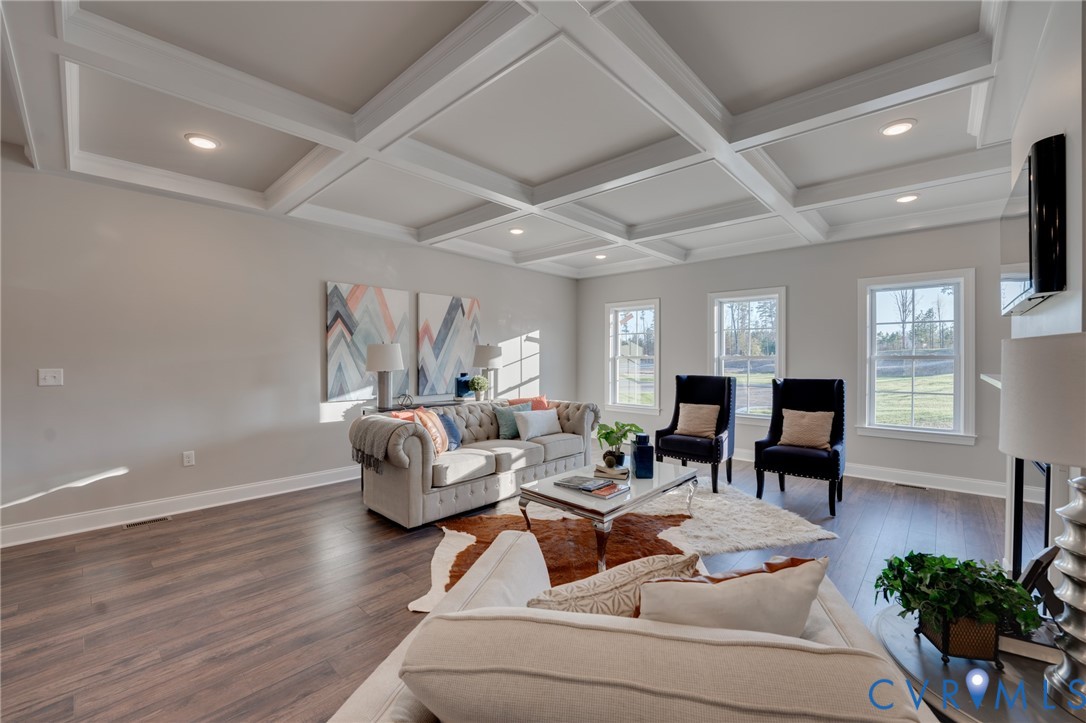 Spacious living area featuring a coffered ceiling, recessed lighting, wood-finish flooring, and multiple windows with white trim