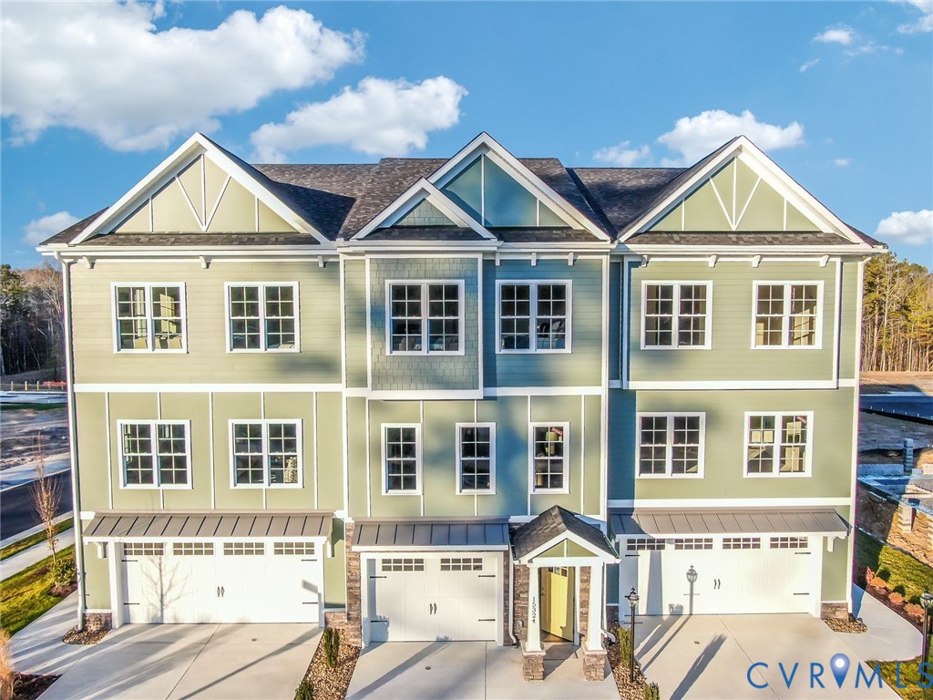 Contemporary townhome exterior featuring multi-toned siding, white trim, multiple gables, a shingled roof, and individual garage doors