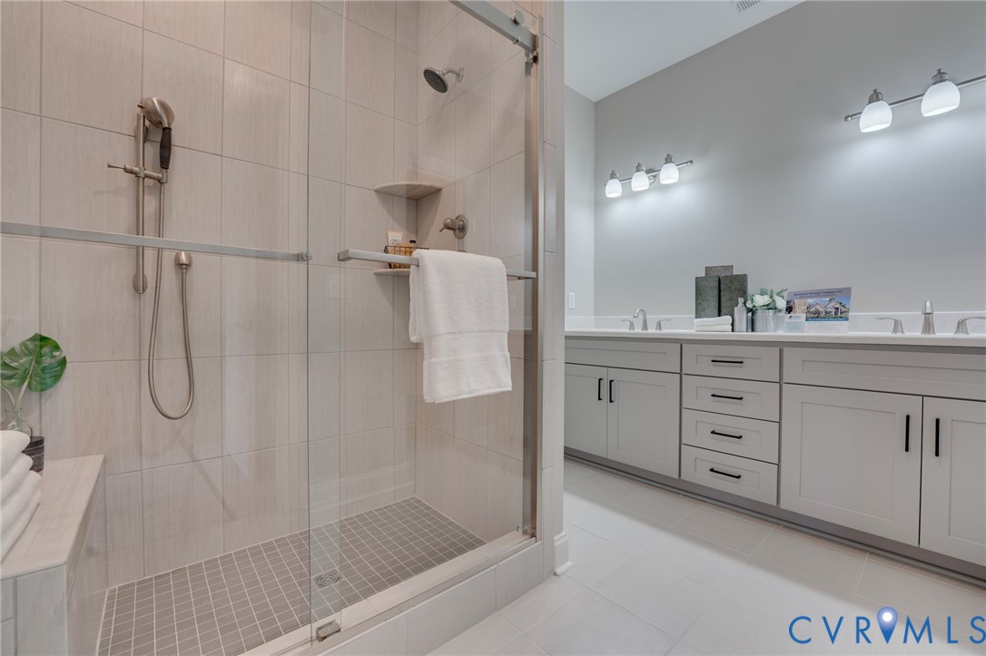Walk-in shower with clear glass enclosure and tile surround
