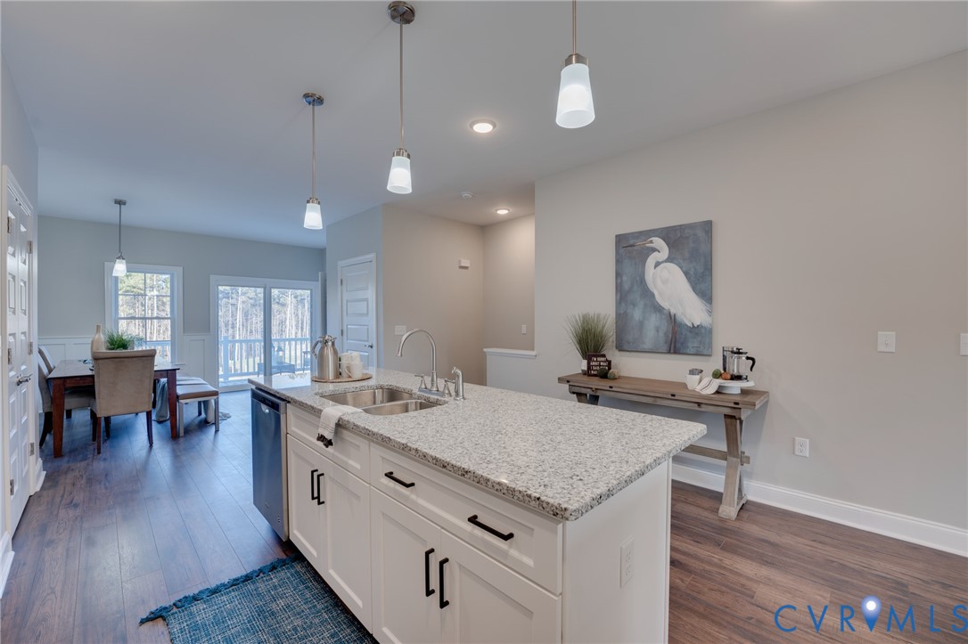 Kitchen island featuring a dual-basin stainless steel sink, a gooseneck faucet, and integrated dishwasher