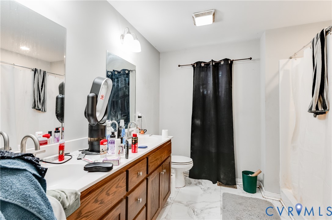 Bathroom featuring a dual vanity with a white countertop and wood cabinetry