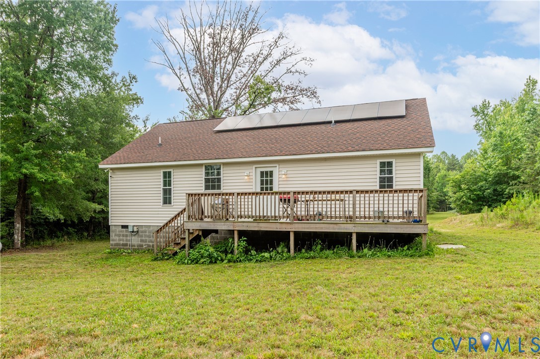 Rear exterior with a spacious wooden deck featuring a wooden railing and stairs