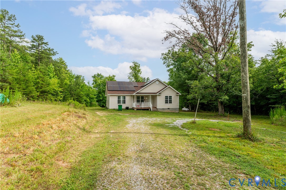 Single-story residence featuring a covered front porch and a gravel driveway