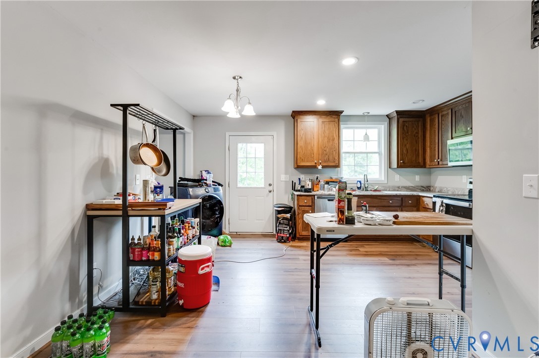 Open-concept kitchen featuring wood-finish flooring, recessed lighting, and a white paneled door Open-concept kitchen featuring wood-finish flooring, recessed lighting, and a white paneled door