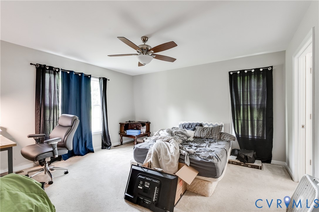 Bedroom featuring light gray wall paint, white trim, two windows, wall-to-wall carpeting, and a ceiling fan