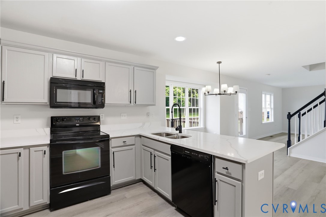 Bright kitchen featuring light-toned cabinetry, white countertops, and black appliances