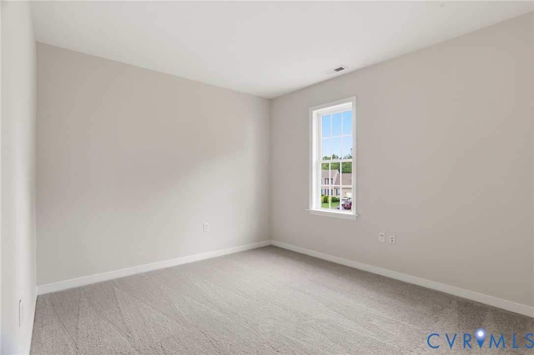 Bright interior space featuring light gray wall paint, neutral gray carpet flooring, and white baseboards