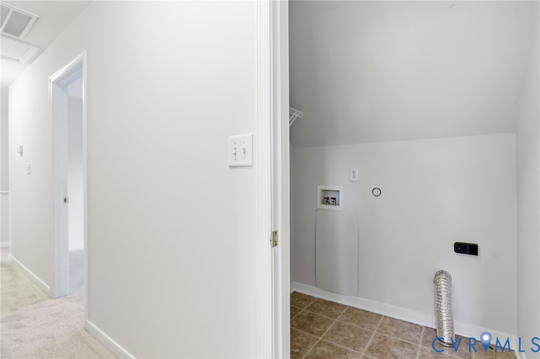 Dedicated laundry area featuring tile flooring, washer hookups, dryer hookup, and overhead storage shelving