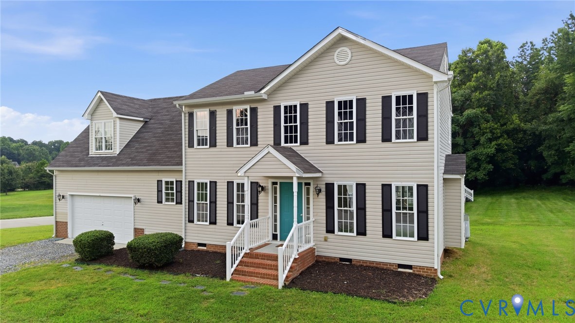 Traditional two-story home featuring light-colored siding, black louvered shutters, an attached two-car garage, and a welcoming front porch with a vibrant turquoise door