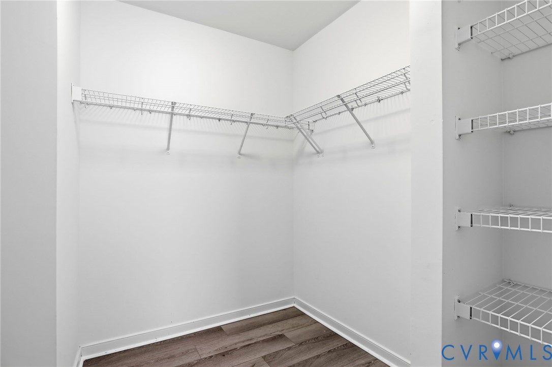 Spacious closet featuring white wire shelving, white walls, and wood-finish flooring
