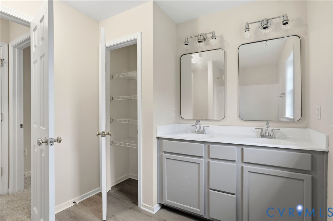 Dual vanity with gray cabinetry, white countertops, and chrome fixtures