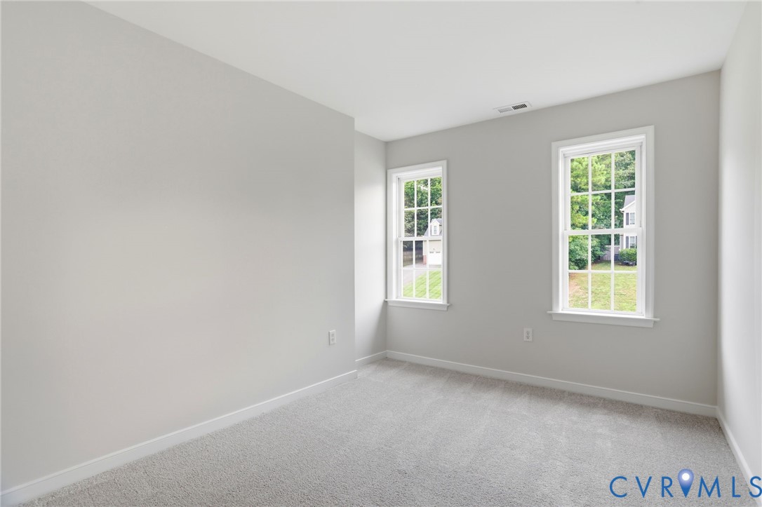 Neutral-toned room featuring light gray walls, two double-hung windows with white frames, and plush carpeting
