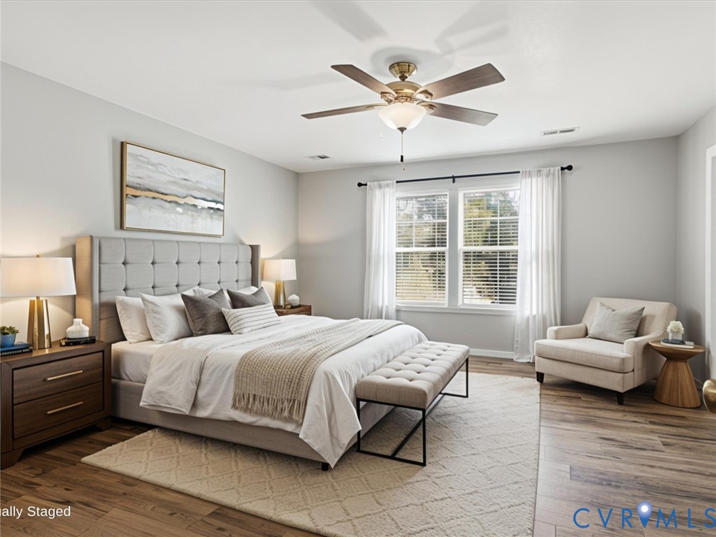 Escape to the expansive primary suite, thoughtfully designed with luxury vinyl plank flooring, oversized windows that fill the room with natural light, a ceiling fan, and ample space for a cozy reading nook or seating area. The oversized walk-in closet offers abundant storage, while the luxurious en-suite bath features a dual vanity and an oversized tiled walk-in shower with a built-in bench, creating the perfect spa-inspired retreat