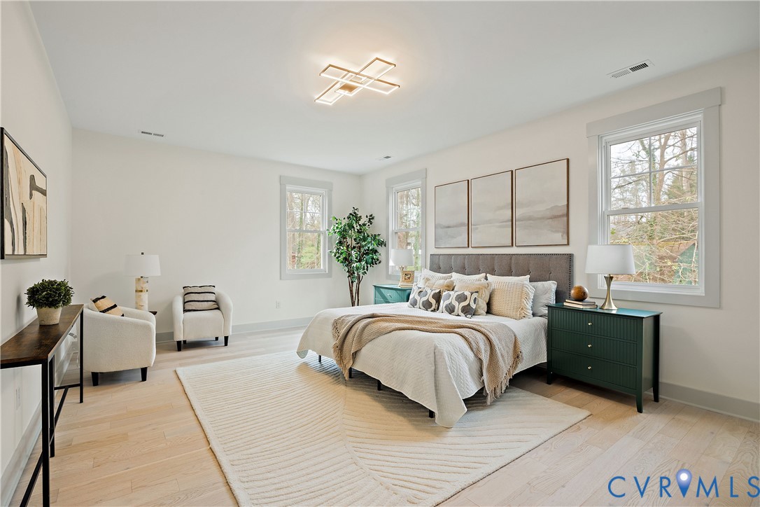 2nd floor primary bedroom featuring light wood-finish flooring, a modern ceiling light fixture, walk-in closet & en-suite bathroom