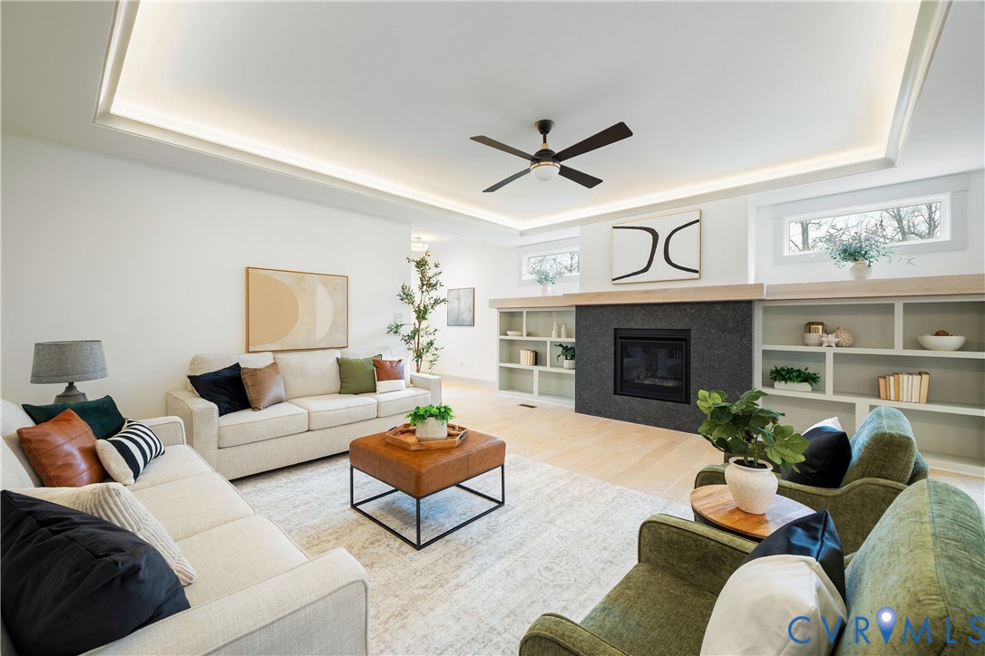 Living area featuring a black stone fireplace surround with a light wood mantel, flanked by built-in shelving and cabinets Living area featuring a black stone fireplace surround with a light wood mantel, flanked by built-in shelving and cabinets