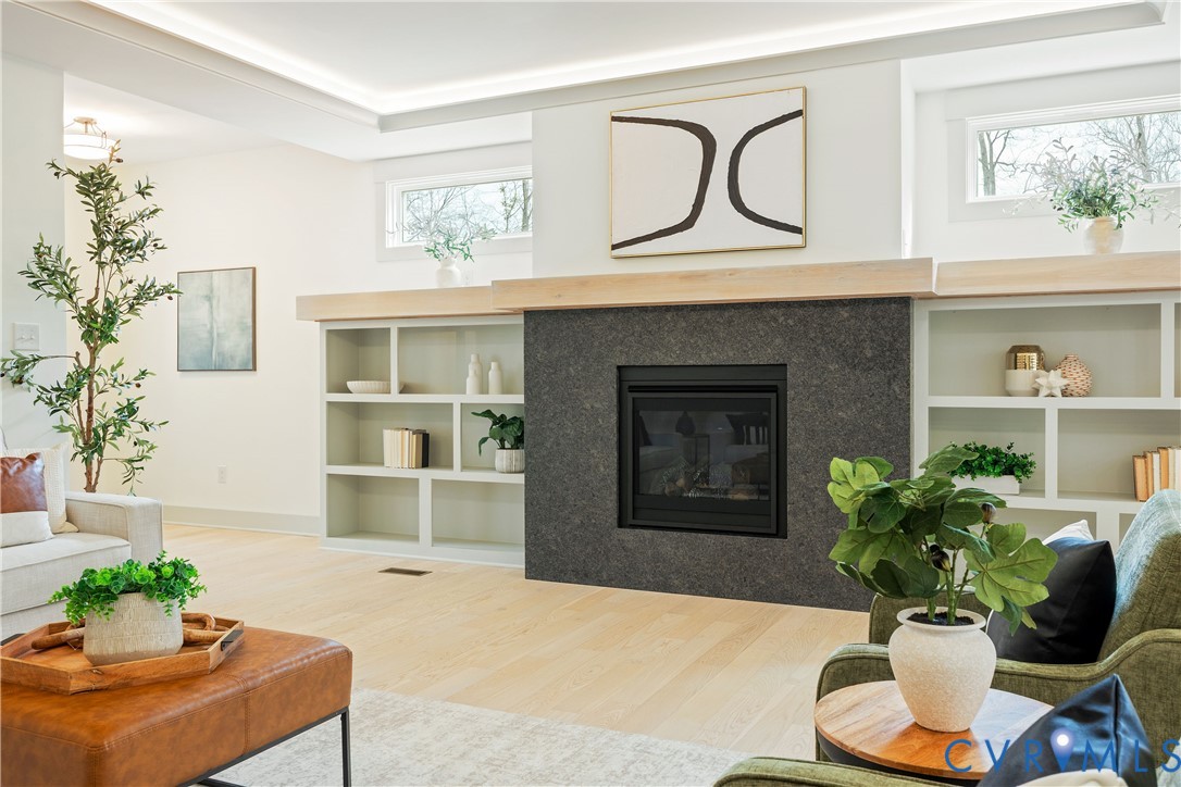 Living space featuring a central fireplace with dark stone surround and a light wood mantel Living space featuring a central fireplace with dark stone surround and a light wood mantel