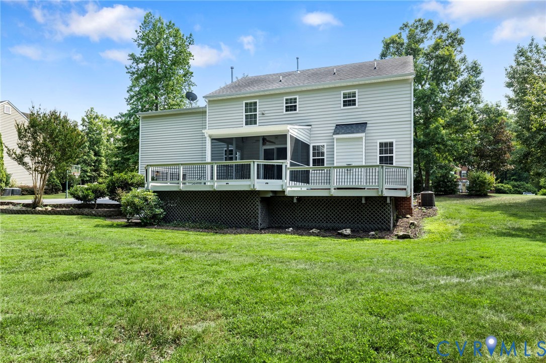 Expansive backyard featuring a multi-level deck with a screened-in porch, light gray siding, and a large grassy area