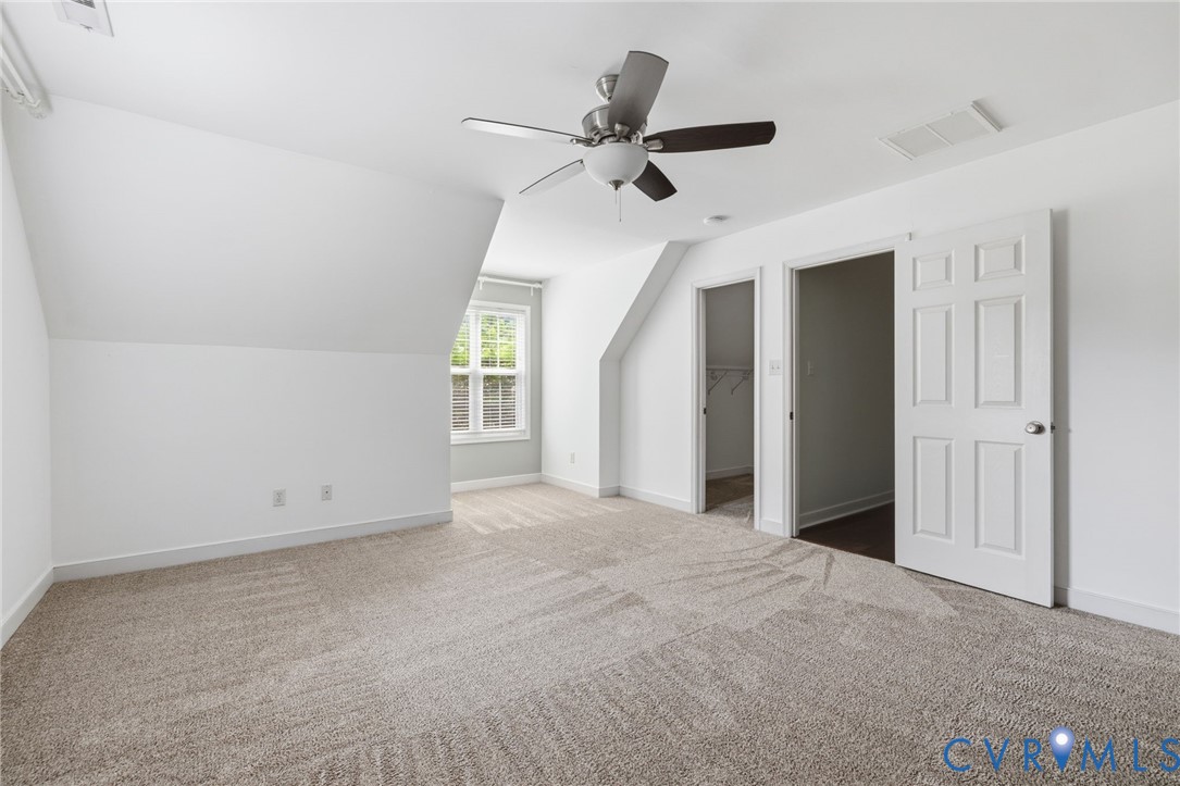 Carpeted room featuring a ceiling fan with light fixture, white trim, and a window providing natural illumination