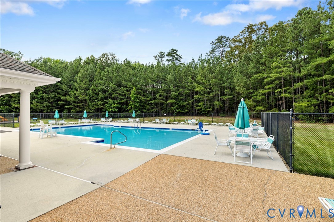 Community swimming pool featuring a large deck, perimeter fencing, and an adjacent covered patio structure
