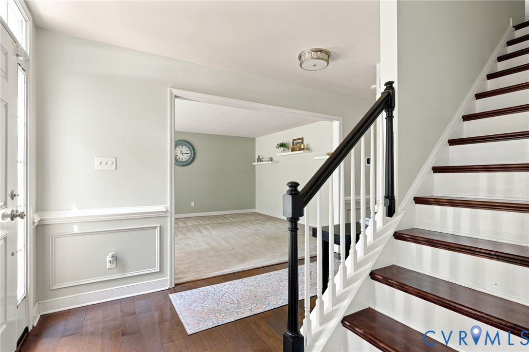 Hardwood-finish flooring, wainscoting, and a staircase with dark wood treads and white risers
