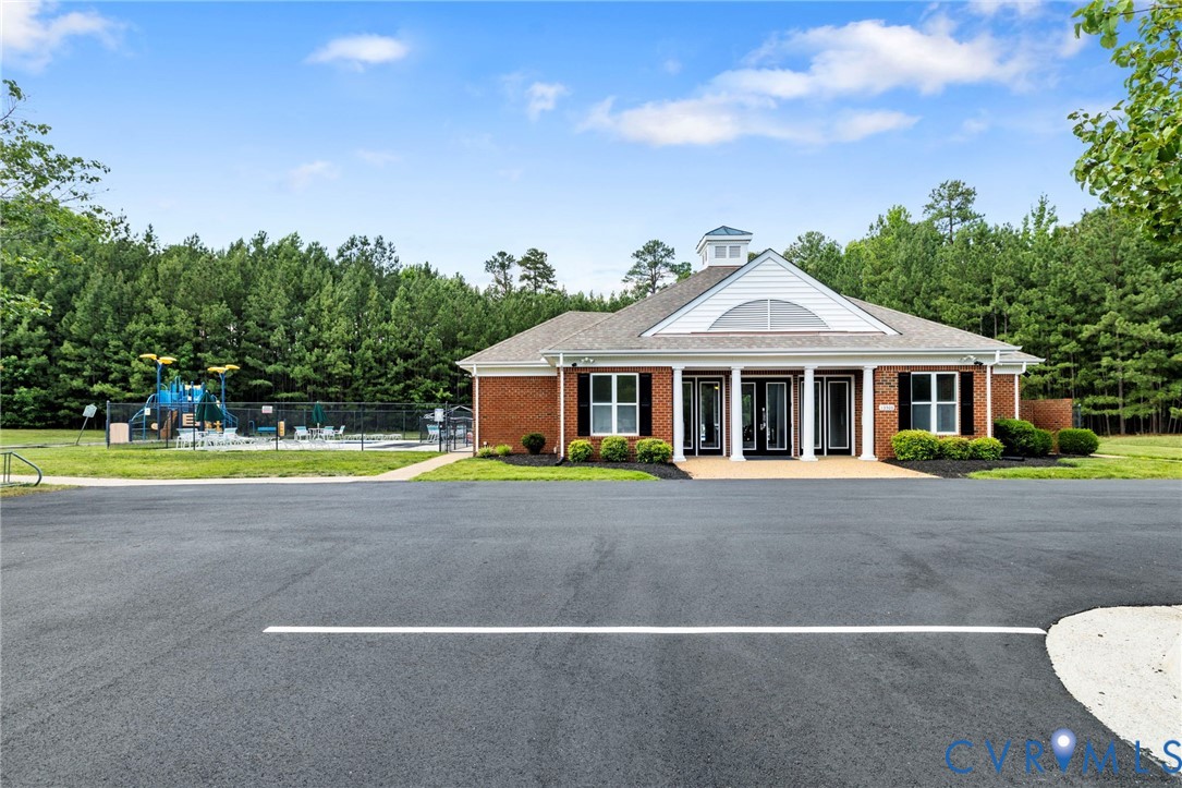 Community clubhouse featuring a brick exterior, white siding, a cupola, and a covered portico entrance with white columns
