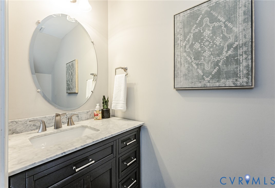 Bathroom vanity featuring a dark wood-finish cabinet with silver-tone hardware, a white countertop, and an undermount sink