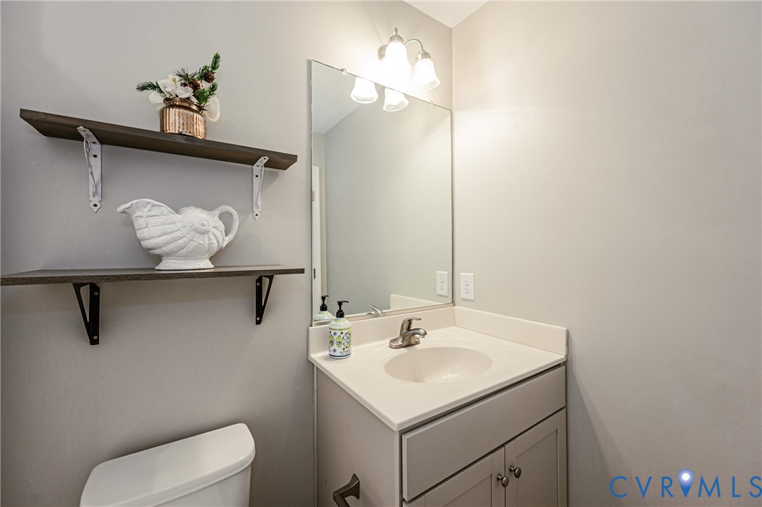 Bathroom vanity featuring a light-toned countertop with integrated sink, brushed nickel faucet, and a mirror with overhead three-bulb light fixture