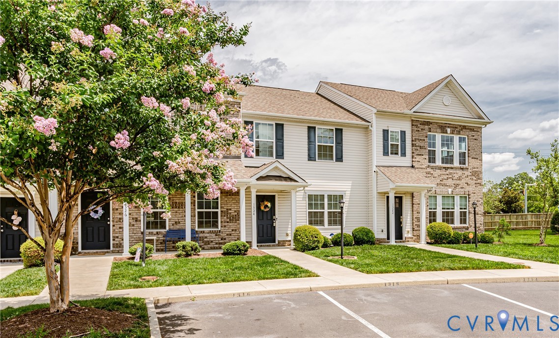 Townhome exterior featuring a combination of light-colored siding and brick accents