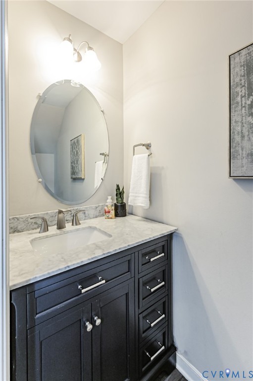 Bathroom vanity with dark wood cabinetry, a white countertop, and an undermount sink