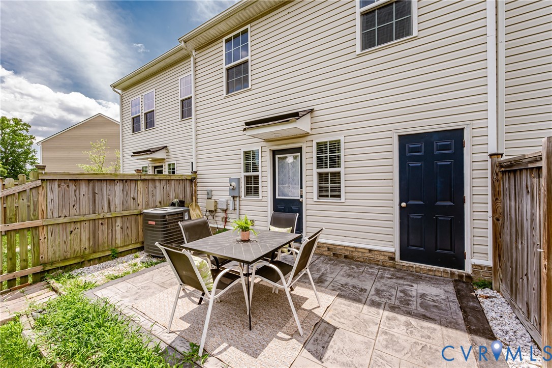 Private outdoor patio space featuring stamped concrete, a full privacy fence, and an exterior storage door