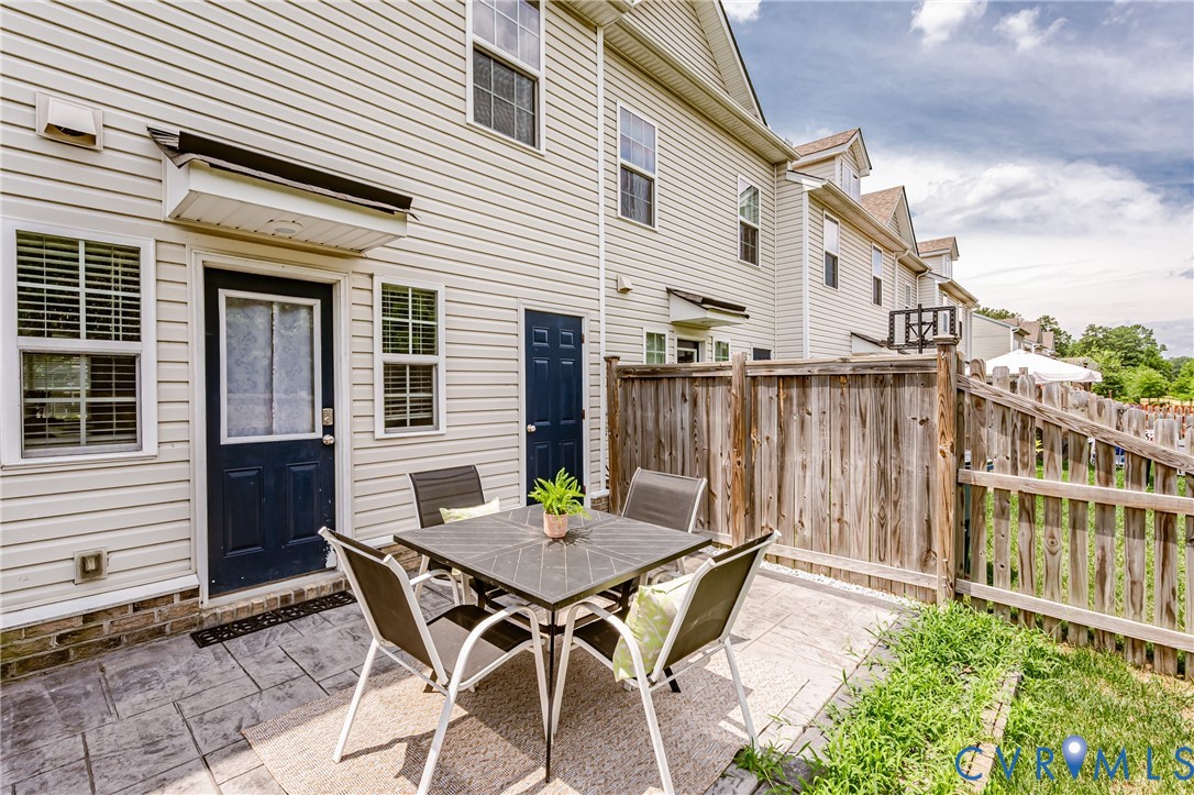 Rear patio featuring stamped concrete, wood fencing, and a manicured grass border