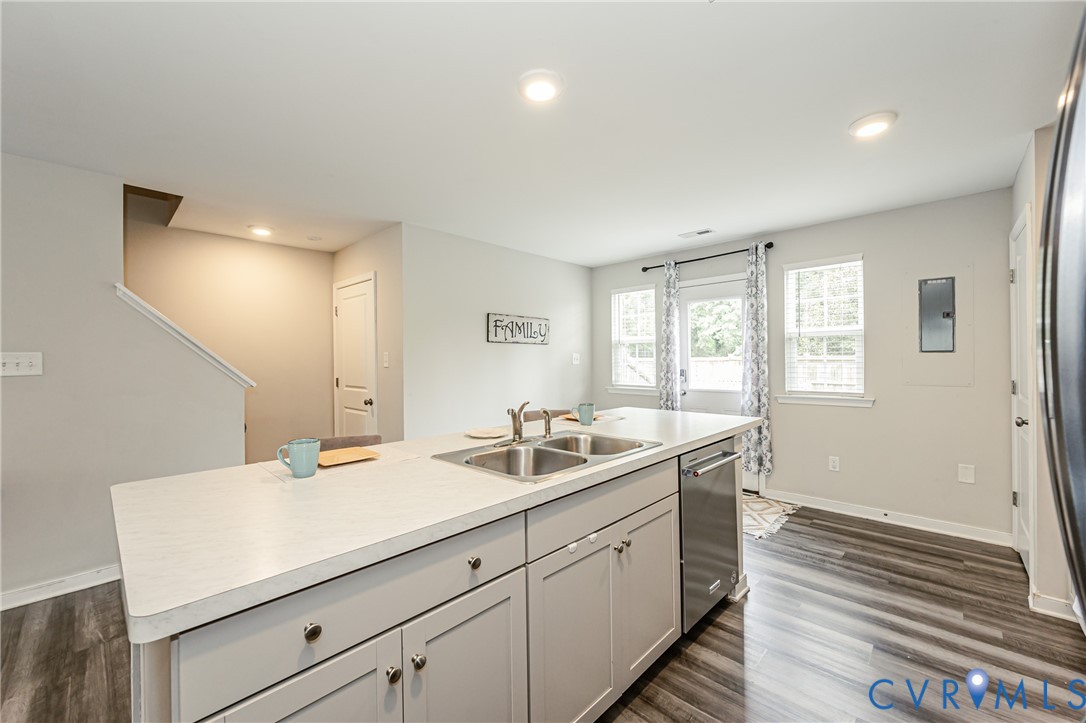 Kitchen island featuring a double-basin stainless steel sink, light-toned countertop, and light gray cabinetry