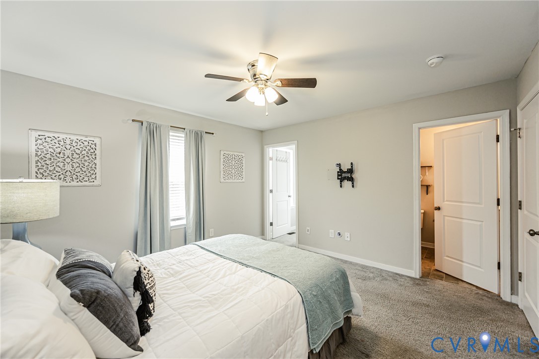 Carpeted bedroom with neutral wall paint and a ceiling fan