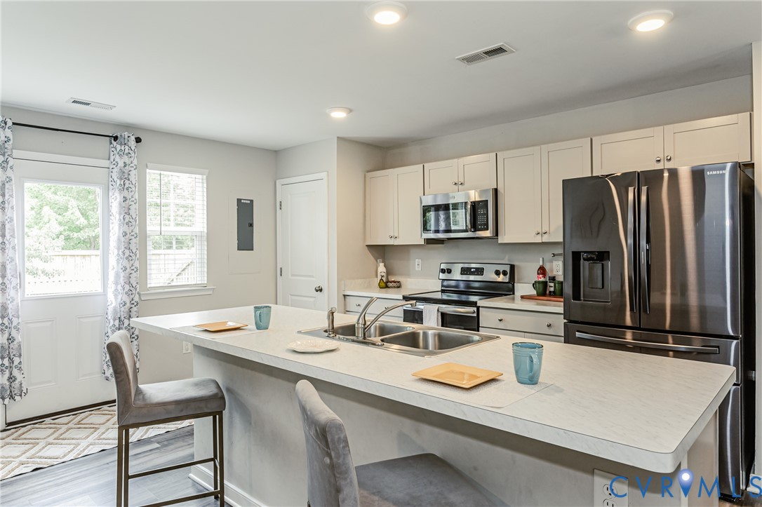 Open-concept kitchen featuring an eat-at island, stainless steel appliances, recessed lighting, and white cabinetry