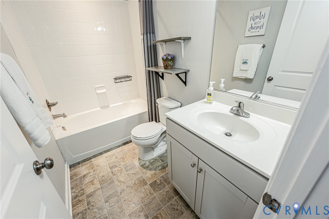 Bathroom featuring a white vanity with integrated sink, chrome faucet, and a large wall-mounted mirror
