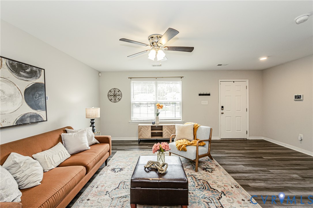 Spacious living area featuring wood-finish flooring, light neutral wall tones, a ceiling fan with integrated lighting, and recessed lighting